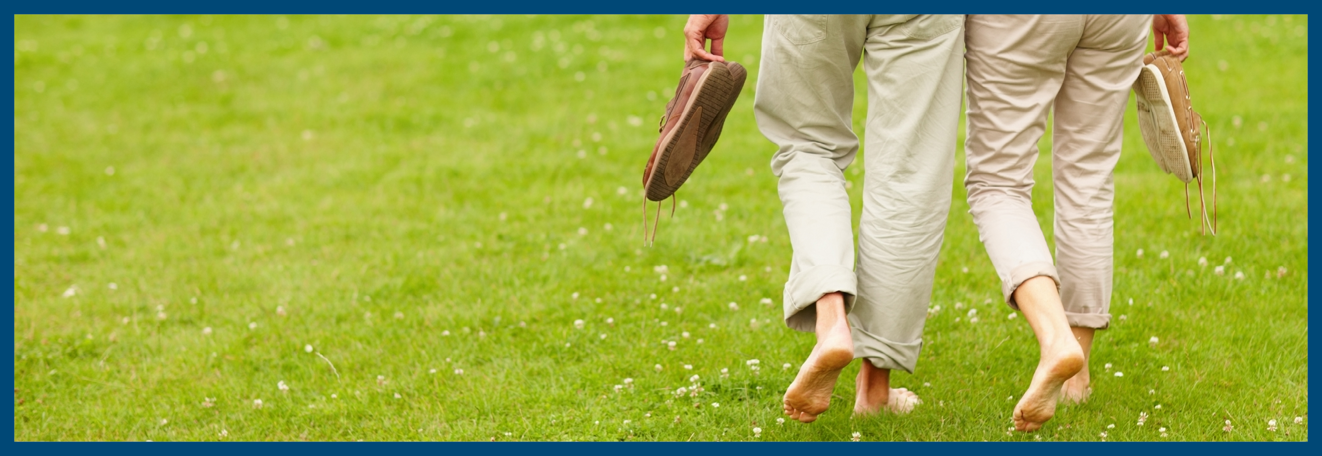 Rear view low section of a couple walking barefeet on the grass at the park